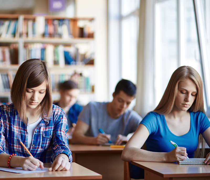 Students write notes in their notebooks during a lecture