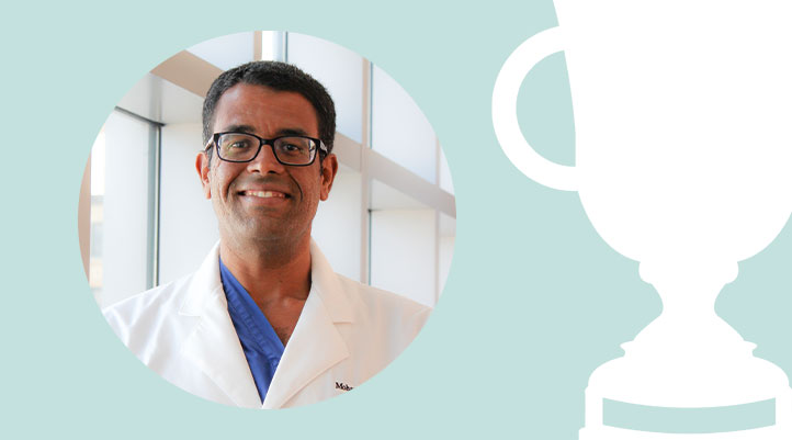 Headshot of Mohamed Ibrahim against a light teal background with a white trophy graphic
