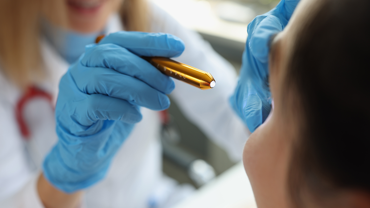 A doctor shines a light to examine a patient's eye